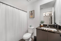 Bright and airy, this bathroom features a sleek dark vanity complemented by a chic mirror and contemporary lighting. The soft white shower curtain adds a touch of freshness, making it a calming space to start your day.