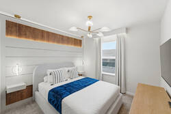 Rest in a bright modern bedroom with a cozy white bed, blue throw, wood accent wall, soft pendant lights, white curtains, wall-mounted TV, and calm neutral details for vacation comfort.