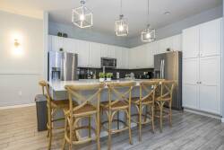 Experience a stylish kitchen with light wood accents and sleek stainless steel appliances, ideal for culinary adventures. The spacious island with inviting bar stools creates a warm atmosphere for gathering and entertaining.