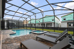 Step into your private oasis with a shimmering pool framed by sleek pavers and comfortable loungers, all under a spacious screened enclosure. Enjoy the sunny blue skies above while soaking in the hot tub, perfect for unwinding.