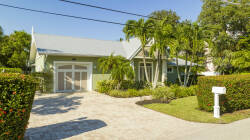 This charming home features a warm façade amid lush greenery and vibrant landscaping, creating a picturesque entrance. Its light-colored exterior enhances the sunlit surroundings, inviting you to explore the comforts within.