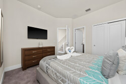 This cozy bedroom offers a plush queen bed with soft bedding and decorative pillows for relaxation after your adventures. Enjoy the sleek wooden dresser and wall-mounted TV, all in a well-lit, calm space perfect for unwinding.