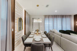 Enjoy our inviting dining area with a sleek white table for six, plush gray chairs, and a stunning chandelier, all designed to create a warm ambiance perfect for memorable shared meals.