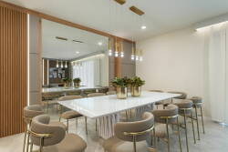 Enjoy our chic dining area featuring a sleek marble table and plush gold-accented chairs, ideal for gatherings. Warm lighting enhances the elegant wood paneling and mirrors, creating a welcoming atmosphere for meals and.