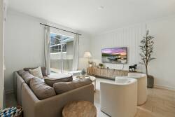 Enjoy the bright natural light in this cozy living room, where soft beige tones of the plush sectional and sleek coffee table invite relaxation. Warm accents like the floor lamp and decorative plant enhance the welcoming ambiance.