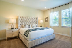 Enjoy the soothing natural light in this beautifully designed bedroom, featuring a plush tufted headboard, soft wall colors, cozy bedding for restful nights, and elegant bedside lamps that set a tranquil atmosphere for your stay.