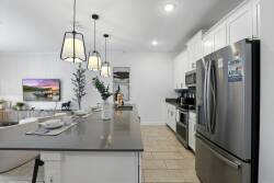 Experience a stylish kitchen with sleek stainless steel appliances and a spacious dark stone island, ideal for casual meals. The warm glow of pendant lighting creates a bright, inviting atmosphere for your culinary adventures.