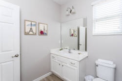 Enjoy a bright and airy bathroom with a sleek white vanity and a large mirror that amplifies the spaciousness. Charming wall art adds character, and natural light floods in, creating a refreshing and inviting atmosphere.
