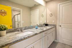 Step into this stylish bathroom featuring a sleek granite countertop and dual sinks, perfect for morning routines. The modern decor is complemented by a vibrant yellow door, adding a pop of color to the inviting ambiance.