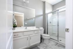 This bright bathroom features sleek white cabinetry and a spacious glass shower, complemented by elegant marble flooring. Enjoy the natural light pouring in, enhancing the clean and refreshing atmosphere for your daily routines.
