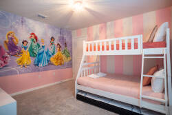 This bright and playful room features a whimsical mural of beloved princesses to delight younger guests. The cozy bunk bed in soft pink invites restful nights, and plush carpeting adds comfort for a perfect stay.