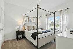 Experience a cozy stay in this elegantly decorated bedroom with a stylish four-poster bed, soft linens, and plush pillows. Large windows bring in natural light, creating a warm and inviting retreat for your relaxation.