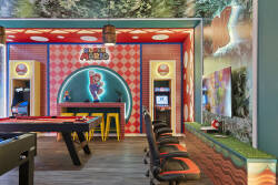Play in a colorful Super Mario game room with a pool table, arcade machine, fun wall art, bright lighting, and bar stools, creating a lively space for family entertainment during vacation.