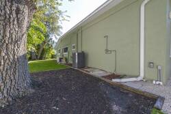Relax in your serene private outdoor space, nestled in lush greenery under a sturdy tree. The charming green siding of the home adds to the inviting atmosphere, inviting you to enjoy the beauty right outside your door.