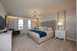 This bright and airy bedroom offers a plush king-size bed with soft linens and a chic chandelier that adds a warm glow. Large windows frame stunning views, creating an inviting atmosphere for a relaxing stay.