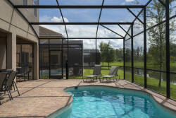 Step outside to enjoy a lovely pool area with a spacious patio, stylish lounge chairs, and a beautiful view of the surrounding greenery, all within a screened enclosure for your comfort and relaxation.