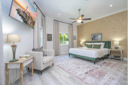 Bathe in natural light as you unwind in this beautifully styled bedroom, featuring a plush queen bed with vibrant teal accents and a cozy seating area. The warm tones of the decor and soft textures invite relaxation and comfort.