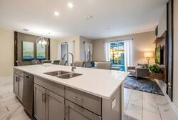 This bright kitchen boasts a stunning white quartz island perfect for mealtime conversations, sleek gray cabinetry, and polished tile flooring, while large windows let in natural light for an uplifting atmosphere.