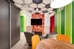 Welcome to a lively lounge featuring playful hexagonal ceilings and bold green and red accents. Unwind in cozy leather seating amidst contemporary decor that inspires creativity and encourages engaging conversations.