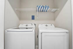 Keep clothes fresh during your stay with a convenient laundry area featuring a washer, dryer, storage shelf, and pool towels, offering extra comfort and practicality for your vacation.