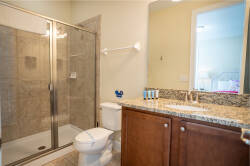 This bathroom features a sleek glass shower and a stunning granite countertop that adds a touch of luxury. The warm wood cabinetry complements the neutral tile, creating a stylish space for your everyday routines.