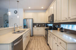 Welcome to this beautiful kitchen with sleek white cabinetry and a spacious quartz countertop, ideal for meal prep. The stainless steel appliances shine under warm lighting, making it an inviting space for your culinary creations.