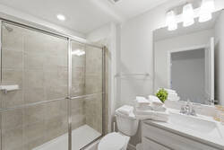Refresh in a bright bathroom with a glass shower, neutral tile, white vanity, large mirror, soft lighting, fresh towels, and clean modern details for vacation comfort.