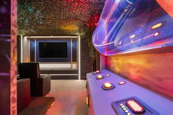 Experience a lively entertainment room with a sleek media wall and a stylish control panel lit by colorful LED lights. The cozy seating invites you to unwind and enjoy movie nights or game sessions with friends.