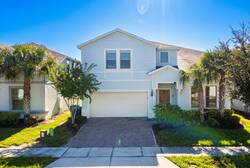 Arrive at a bright two-story vacation home with a private garage, paved driveway, palm trees, and fresh landscaping, creating a welcoming first impression for your Florida vacation.
