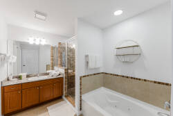 Step into this well-appointed bathroom featuring warm wood cabinetry and elegant tile accents. The spacious soaking tub invites relaxation, while modern fixtures and soft lighting create a calming atmosphere for your stay.