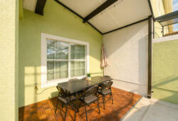 Enjoy a delightful outdoor dining nook with a sleek black table and comfy chairs, all illuminated by natural light from a large window. The high ceiling and soft green walls create a refreshing atmosphere for leisurely meals.
