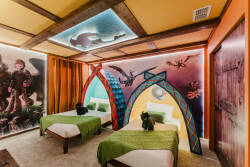 Bright colors and whimsical murals create a playful atmosphere in this unique bedroom, featuring two comfy beds adorned with fresh green linens. The creative design elements invite guests to relax and enjoy a truly memorable stay.