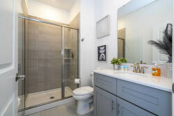 This bright bathroom features a sleek glass shower with modern gray tiles, complemented by a stylish vanity with a marble countertop. The clean lines and thoughtful decor create a refreshing atmosphere for your daily routines.