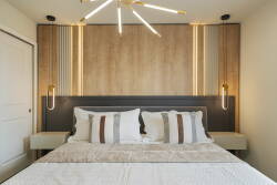 Enjoy restful nights in this beautifully designed bedroom with a stunning wood-paneled accent wall and plush bedding. Stylish lighting enhances the contemporary vibe, creating a warm ambiance for your stay.