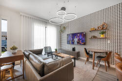 This stylish living area features a striking accent wall and warm leather seating, offering a cozy yet modern vibe. With ample natural light and a sleek dining setup, it's ideal for enjoying meals or planning your next adventure.