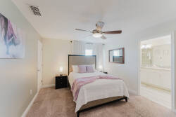 Awake refreshed in this cozy bedroom, featuring soft pastel tones and plush carpeting that invite relaxation. The sleek ceiling fan adds a touch of comfort, while the adjoining bathroom enhances convenience for your stay.