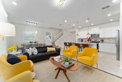 Bright yellow accent chairs add a cheerful touch to the open living area, where natural light highlights the modern decor. The cozy black sofa and stylish coffee table create a welcoming atmosphere for your relaxing stay.
