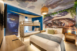 Experience whimsy in this uniquely designed bedroom with a stunning night sky mural. Cozy bunk beds and a plush main bed create a playful yet comfortable space, ideal for relaxing after a day full of adventure.