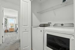 Discover this practical laundry nook with modern white appliances and plenty of shelf space for your essentials. The bright light from the adjacent room creates a welcoming atmosphere, making laundry chores feel less daunting.