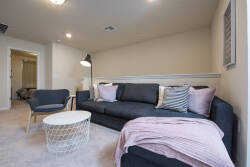 Relax in this cozy living area, featuring a plush dark sofa adorned with soft pink and striped throw pillows. A stylish round coffee table adds a touch of modern charm, while warm lighting creates a welcoming atmosphere.