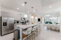 Experience a modern kitchen featuring sleek stainless steel appliances and elegant white cabinetry. The spacious island with stylish bar stools creates a perfect casual dining spot in a warm, inviting atmosphere filled with.