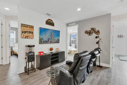 Enjoy a cozy cinema lounge with leather recliners, a wall-mounted TV, popcorn machine, movie decor, and open access to nearby bedrooms, perfect for relaxing movie nights.