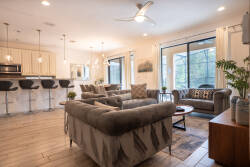Welcome to this bright living area, where natural light pours in through large windows. The cozy sectional beckons you to relax, while the stylish coffee table and modern bar stools create a perfect blend of comfort and elegance.