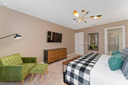 Unwind in this cozy bedroom with a stylish green accent chair and elegant wooden dresser against warm, neutral walls. A modern light fixture adds flair, and the comfy bedding ensures you'll enjoy restful nights.