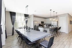 Unwind in our spacious dining area with a sleek table and stylish black chairs, perfect for gatherings. The large windows bring in sunlight, enhancing the modern kitchen and creating a warm, inviting atmosphere for you and your.