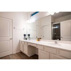 Refresh in a spacious bathroom with a long vanity, large mirror, bright lighting, and a glass-enclosed shower. Neutral tones, wood-look floors, and clean finishes create a comfortable space to relax during vacation.