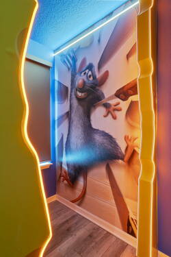 Step into a whimsical hallway that features a vibrant mural of a beloved rat chef, surrounded by bold, colorful wall accents and playful lighting. The unique design invites creativity and fun, making every moment feel special.