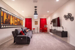 Step into a vibrant living room where bold red curtains complement the contemporary decor. A plush gray sofa invites relaxation, while striking artwork adds a touch of personality to the inviting atmosphere.
