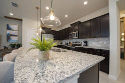 Discover a culinary haven in this stylish kitchen, where rich dark cabinetry contrasts beautifully with striking granite countertops. Enjoy the warm ambiance from pendant lights as modern appliances make every meal a delight.