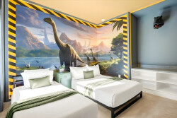 Welcome to a vibrant bedroom featuring a striking dinosaur mural that ignites your imagination, paired with crisp white bedding and soft green accents, creating a playful and unique atmosphere perfect for adventurous spirits.